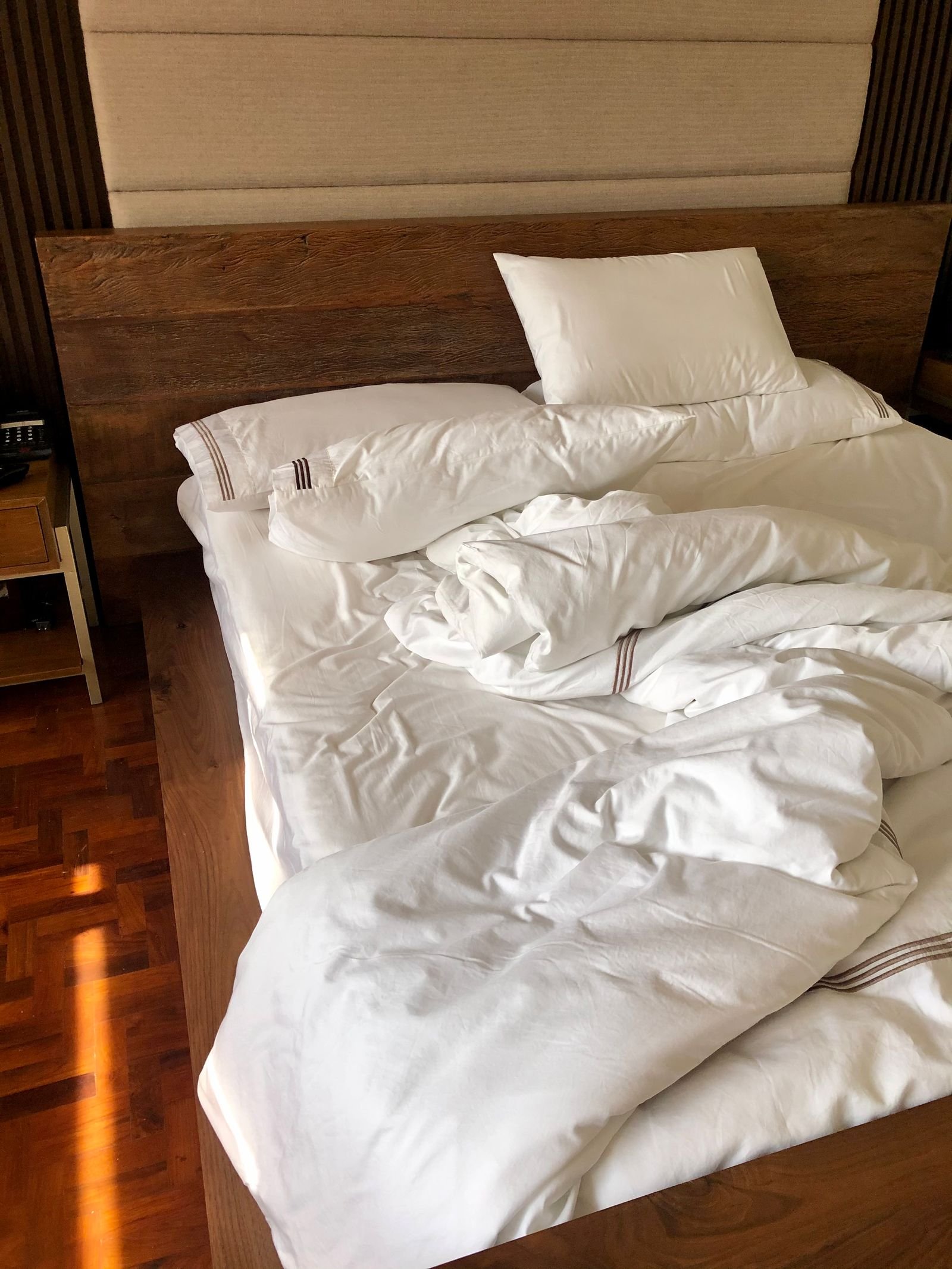 Bed made up with fresh white linen in a managed unit, lit by daylight