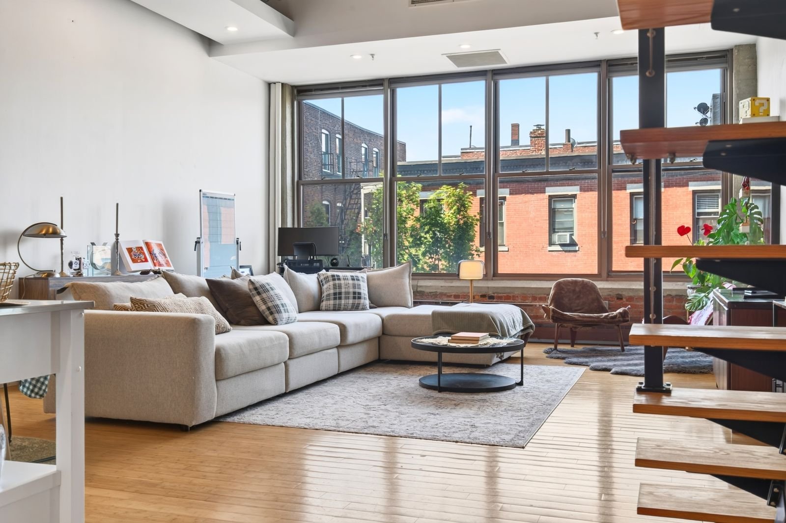 Bright loft living space with tall industrial windows, furnished for guests
