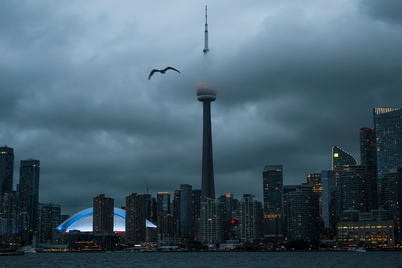 The CN Tower and Toronto skyline under low cloud at dusk