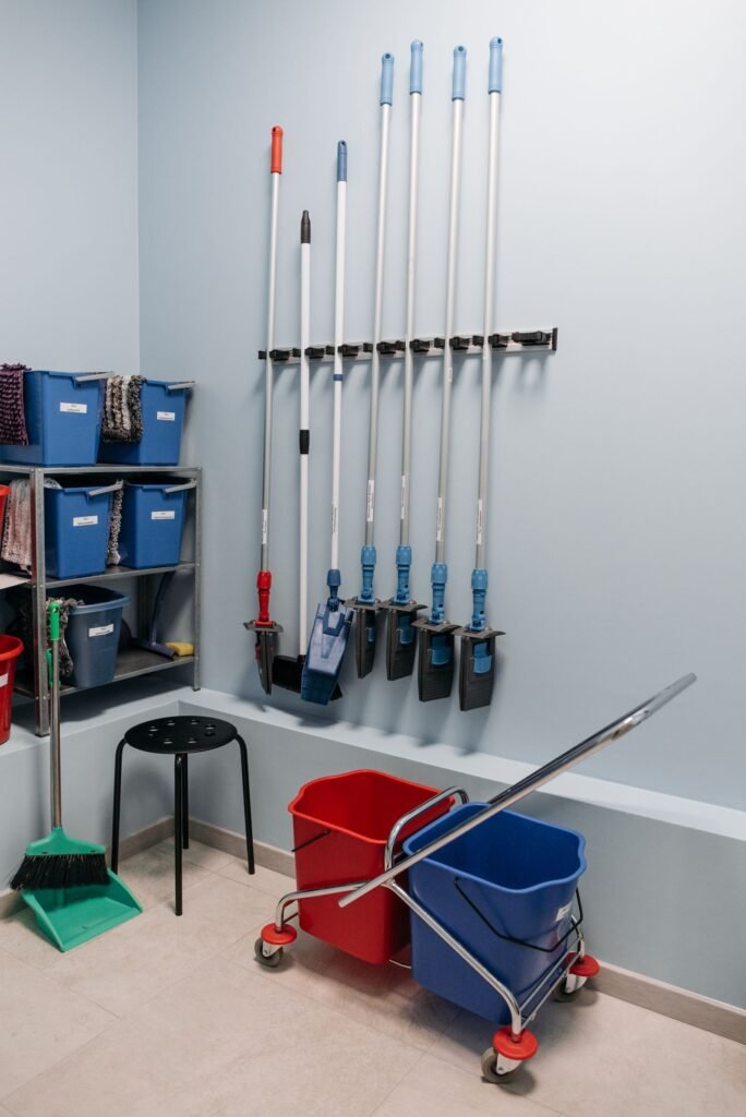 Cleaning equipment neatly arranged in a storage room with mops and buckets